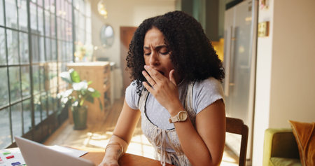 Tired, woman and yawn in home with laptop for remote work burnout, interior design stress and fail. Exhausted, freelancer and creative person in apartment with computer, mistake or deadline pressure.の写真素材
