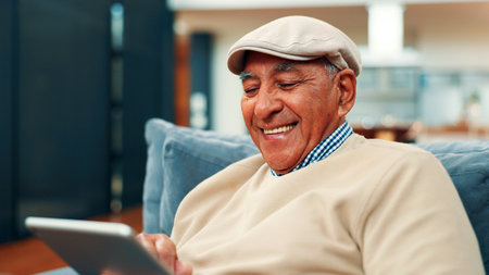 Tablet, smile and senior man on sofa in home with connection, social media or blog post. Retirement, digital technology and elderly person in living room for reading news headline on app in house.の写真素材
