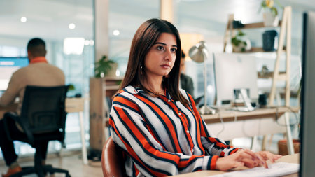 Serious, employee and woman with computer, office or journalist with story for magazine and creative. Newsroom, reporter and person with technology for article publication, productivity and coworkingの写真素材