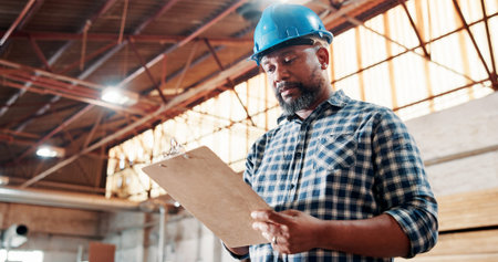 Black man, carpenter and clipboard with checklist for woodwork, project or inventory in warehouse. Male person, carpentry or list in furniture business for wood construction or stock check in depotの写真素材