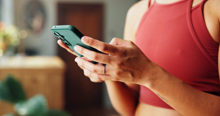 Woman, hands and research with phone for health tips, workout routine or fitness guide in home. Closeup, female person or typing with mobile smartphone for online app or exercise schedule in houseの写真素材