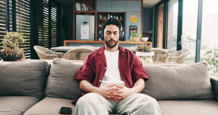 Calm man, sofa or listening with headphones to music for audio therapy, relaxation or stress relief. Male person, relax or user with sound on couch for entertainment, podcast or streaming in houseの写真素材