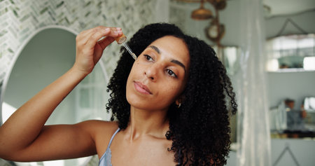Skincare, facial serum or woman in house with pipette, hydration or vitamin C benefits in soft skin. Dermatology, glow or girl in bathroom with oil dropper, collagen or shine in anti aging treatment.の写真素材