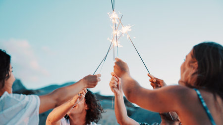 People, hands and sparkler with blue sky for new year, outdoor event or social gathering. Group, friends or fireworks with stick in celebration for holiday, weekend or bonding together in natureの写真素材