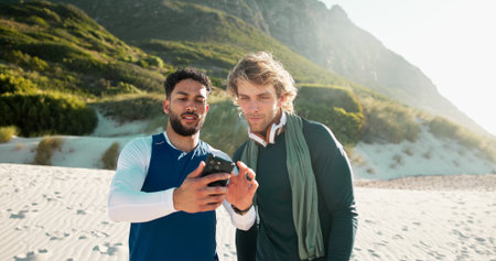 Outdoor, smartphone and men with exercise, internet and online reading with communication. People, fitness and friends with cellphone, network and sand with social media and app to track progressの写真素材