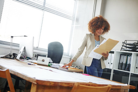 Business woman, secretary or checking documents with folder, company policy or regulations. Female person, employee or admin with paperwork, file or project report for terms and conditions in officeの写真素材