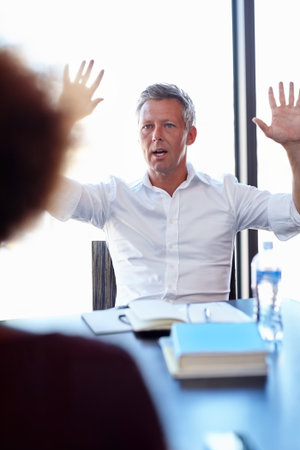 Blame, meeting and stress with business man in office for crisis, feedback or performance review. Anger, frustration and mistake with boss speaking to employee at desk in workplace for accountabilityの写真素材