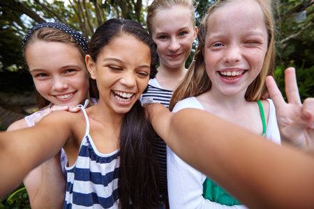 Happy girl, kids or playing with selfie for friendship, bonding or outdoor fun together in nature. Teenagers, group or smile with picture or peace sign for photography, capture moment or social mediaの写真素材