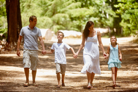 Holding hands, happy or family in woods with walk, connection or bonding on summer break. Smile, parent or kids in forest with stroll, healthy relationship or childhood development in spring getaway.の写真素材
