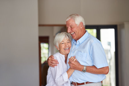 Old couple, love or hug in house with smile for healthy relationship, retirement and bonding together. Married, elderly people and embrace in apartment with happiness for support, commitment or care.の写真素材