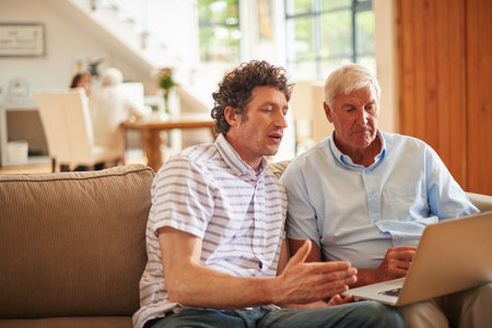 Laptop, teaching and elderly dad with man in home for social media, visit or bonding. Support, family and online with senior father for adult son, tech and help for internet safety for retirementの写真素材