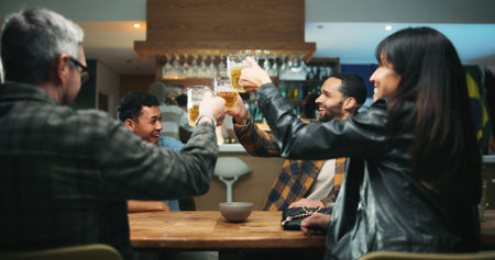 Friends, toast beer and celebration at bar, excited and bonding at party, happy hour and drinks. People, glasses and cheers at pub with alcohol, success or social gathering with reunion at nightの写真素材