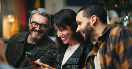 Smartphone, people and friends in pub, smile and social media with communication. Men, online humor and cellphone with internet, connection and digital app with website info, funny meme and happinessの写真素材