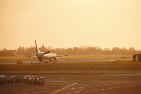 Airport, plane and take off on runway with cargo trailer, flight and global transport at sunset. Airplane, truck and tractor for loader, space and sky for international travel with vehicle on tarmacの写真素材