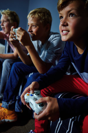 Gaming, challenge and teens on sofa in home with friends, playing and online entertainment. Competition, living room and boys with controller for video games, esports and winning on weekend togetherの写真素材