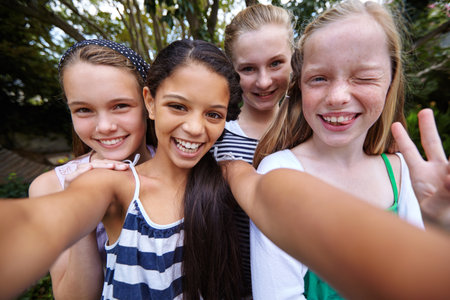Happy girl, kids or portrait with selfie for friendship, bonding or outdoor fun together. Teenagers, group or smile with picture or peace sign for photograph, capture moment or social media in natureの写真素材