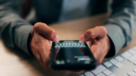 Hands, phone screen and text message with business person at desk in office for communication. App, fingers and typing with employee in workplace for mobile chatting, post update or reply closeupの写真素材