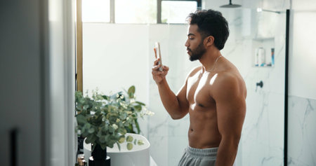 Man, selfie and bathroom mirror with muscle in home for results, shirtless or profile on web in morning. Person, influencer and bodybuilder with photography, content creation or social media at houseの写真素材