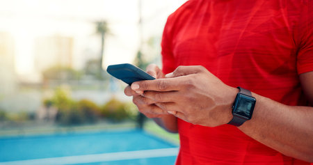 Hands, man and typing with phone on tennis court with fitness app, training tips and track progress. Person, mobile and reservation for padel, technique and video demonstration for sports tournamentの写真素材
