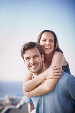 Portrait, beach and happy couple with piggy back, vacation and bonding together. Seaside, summer...
