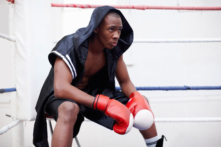 Black man, boxer and getting ready in gym for workout, self defense exercise or mindset for fighting. Serious, prepare and african person or athlete for fitness, endurance or challenge in boxing ringの写真素材