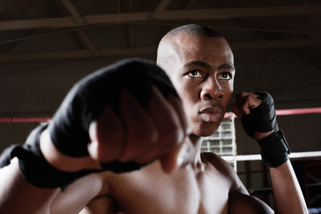 Athlete, black man and boxing with punch in ring for fitness, physical strength and fighting match. Male boxer, exercise or fist impact for mma challenge, power training and sports defense for combatの写真素材