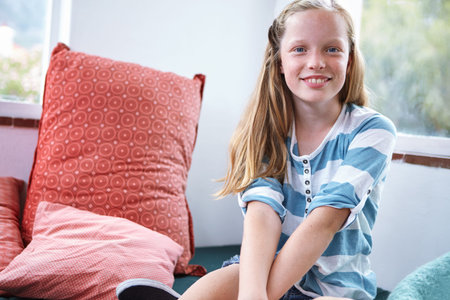 Portrait, relax and smile of girl child in bedroom of home for break, development or growth. Proud,...
