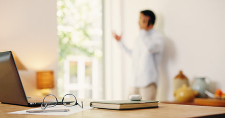 Man, phone call and laptop for remote work at house for consultation, contact source and feedback. Journalist, discussion and glasses with notebook, editing manuscript and fact check for publicationの写真素材