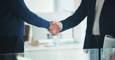 Handshake, partnership and business men in office with deal, finance contract or greeting. Welcome, negotiation and financial manager shaking hands with client for investment proposal in workplaceの写真素材