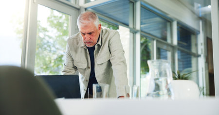 Laptop, reading and serious with man in office for planning, problem solving or research as editor. Computer, publication and review with mature employee at desk in workplace for online magazineの写真素材