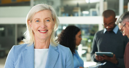 Mature woman, portrait and meeting at office with smile, pride and career. Person, happy and with confidence, or job with group in workplaceの写真素材