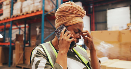 Warehouse, supervisor and woman with stress, phone call and talking with contact for shipping delay. Factory, distributer and black person with anxiety for distribution fail, mobile and supply chainの写真素材