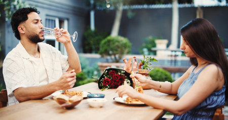 Date, drinking and eating with couple in restaurant together for anniversary, bonding or love. Champagne, food and romance with people at table for fine dining cuisine, gourmet meal or pasta dishの写真素材