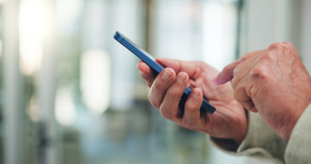 Person, hands and typing in office with phone for business email, online communication and text message. Employee, scroll and internet in workplace with tech for company website, mobile app or space.の写真素材