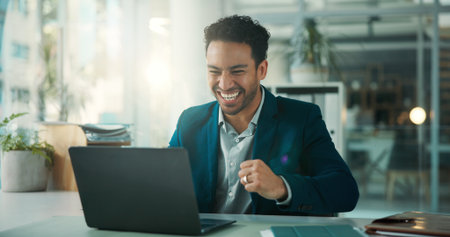 Finance, fist pump and laptop with business man at desk in glass office for accounting success. Computer, investment management and victory with broker in financial workplace for portfolio targetの写真素材