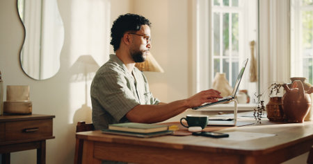 Typing, man and research with laptop, home and creative for logo design on web or freelance project. Graphic designer, online and person with tech for digital art, technical skills and remote workの写真素材