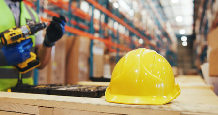 Logistics, person and helmet on crate in warehouse for cargo assembly, supply chain or compliance....