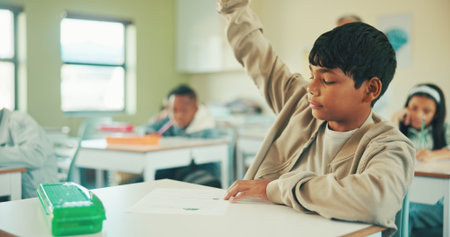 Quiz, raised hands and question with boy in classroom for student opinion, assessment and attention. Course guidance, help and problem solving solution with children in school for lesson and studyの写真素材