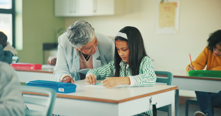Help, teacher and quiz with girl in classroom for student opinion, assessment feedback and attention. Course guidance, advice and problem solving solution with children in school for lesson and studyの写真素材
