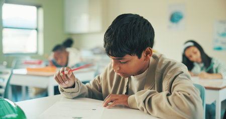 Writing, education and quiz with boy in classroom for test, child development and knowledge. Studying, assessment and academy with student on school campus for learning, course curriculum and examの写真素材