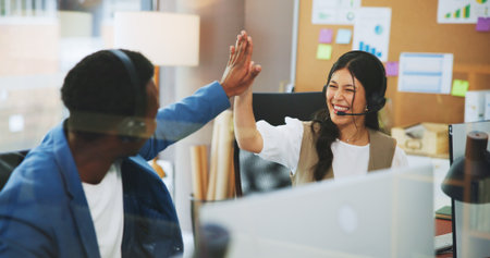 Business people, consultant or high five with headset in office for online advice or virtual assistance. Businessman, woman or coworking with smile for team success, help or support in workplaceの写真素材