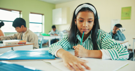 Classroom, thinking or child with book for learning, development or assessment for maths education. Remember info, contemplating question or girl with pencil for test, answer ideas or problem solvingの写真素材