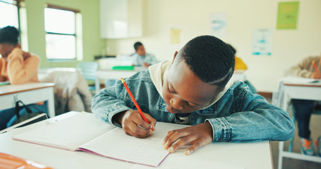 Classroom, child and writing notes in book for learning, maths lesson and practice sums for...