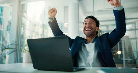 Celebration, fist pump and laptop with business man at desk in financial office for accounting success. Computer, investment management and target with finance broker in workplace for bonus or goalsの写真素材