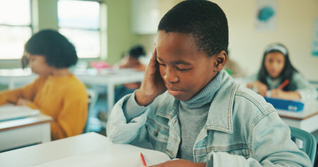 Thinking, education and quiz with boy in classroom for idea, child development and knowledge. Studying, assessment and academy with student on school campus for problem solving, learning and examの写真素材