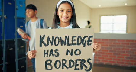 Portrait, school and girl with banner, protest and education with placard, activism and study. Learning, student and child development in hallway, basic rights and sign with promote equality or smileの写真素材