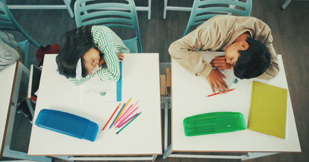 Sleeping, students or kids in classroom with fatigue from difficult english quiz, assessment or activity. Above, exhausted learner or children nap in school with burnout from learning, study or test.の写真素材
