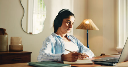 Remote work from home, writing and woman with laptop, headphones and notes for creative project. Apartment, freelancer and person with computer, notebook or listening to music, radio and website infoの写真素材