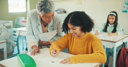 Writing, teacher and quiz with girl in classroom for student opinion, assessment feedback and attention. Course guidance, help and problem solving solution with children in school for lessonの写真素材