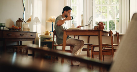 Creative, coffee and man with laptop, home and research for logo design on web or freelance project. Graphic designer, online and person with tech for digital art, drinking and remote work with teaの写真素材